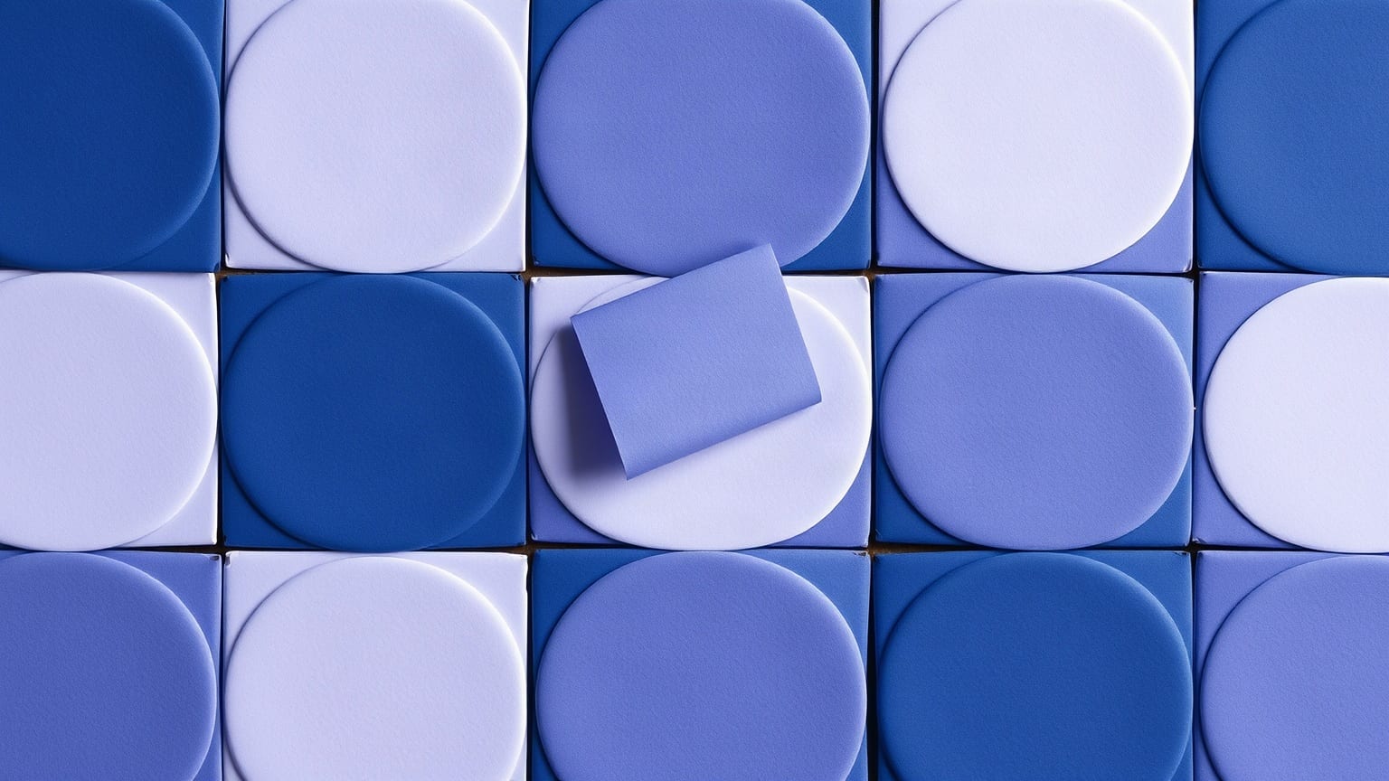 Cut-paper illustration: a grid of rounded tiles with one tile lifted and turned over.
